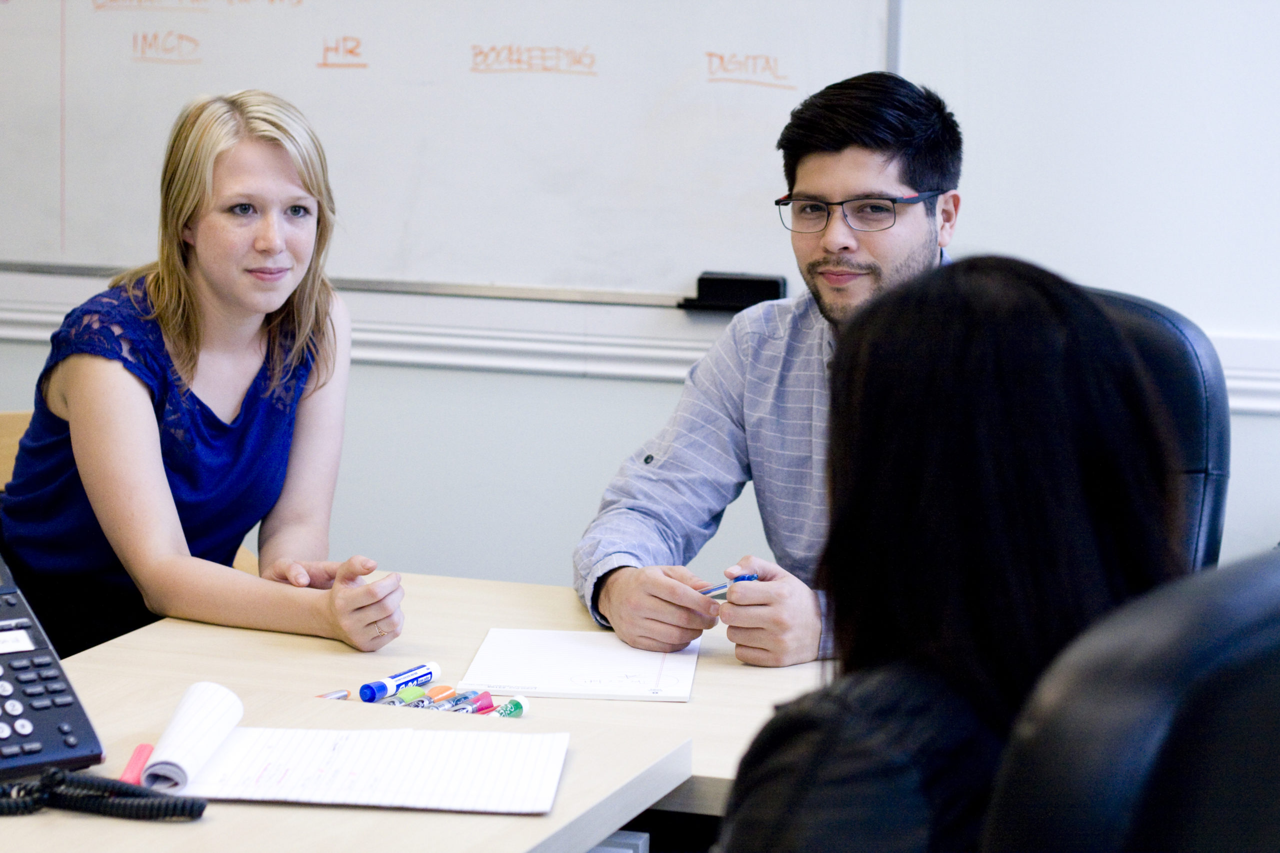 Two professionals sit at a desk preparing for a discussion