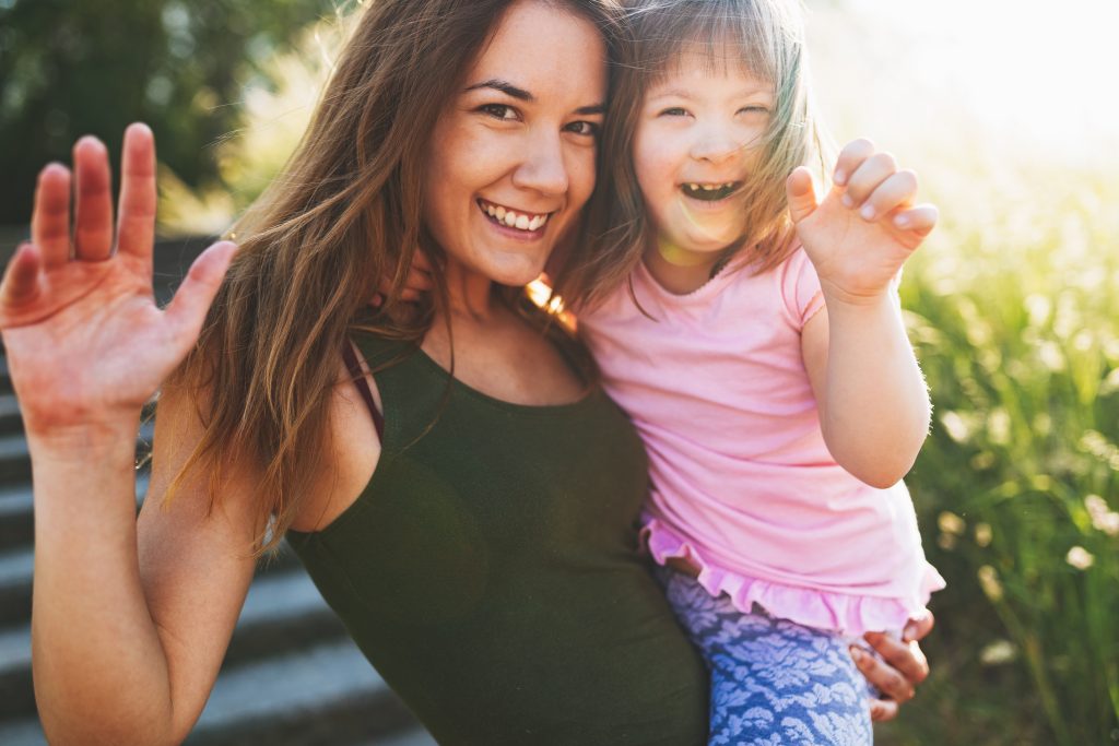 A woman with her special needs child on her hip waving 