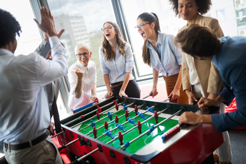 Office employees playing a game of foosball in an office