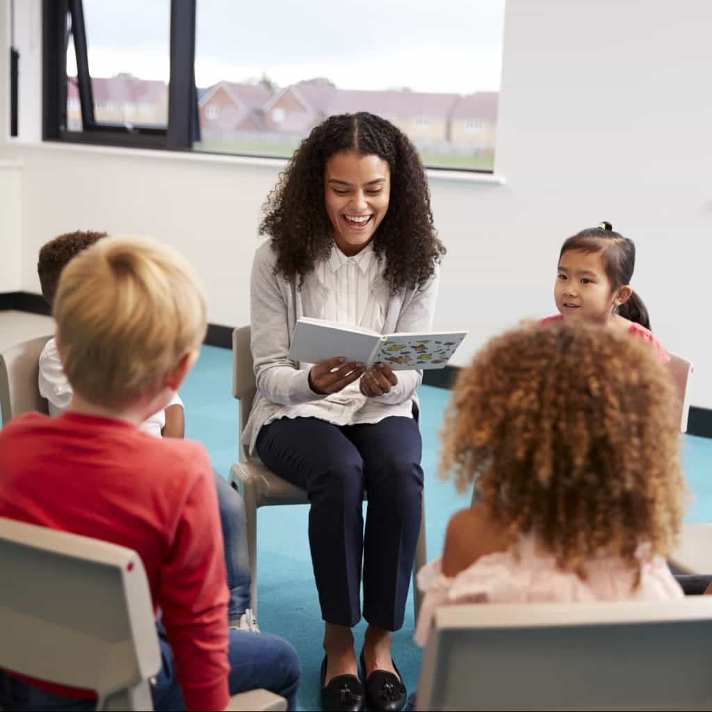 An education assistant reads aloud to her students