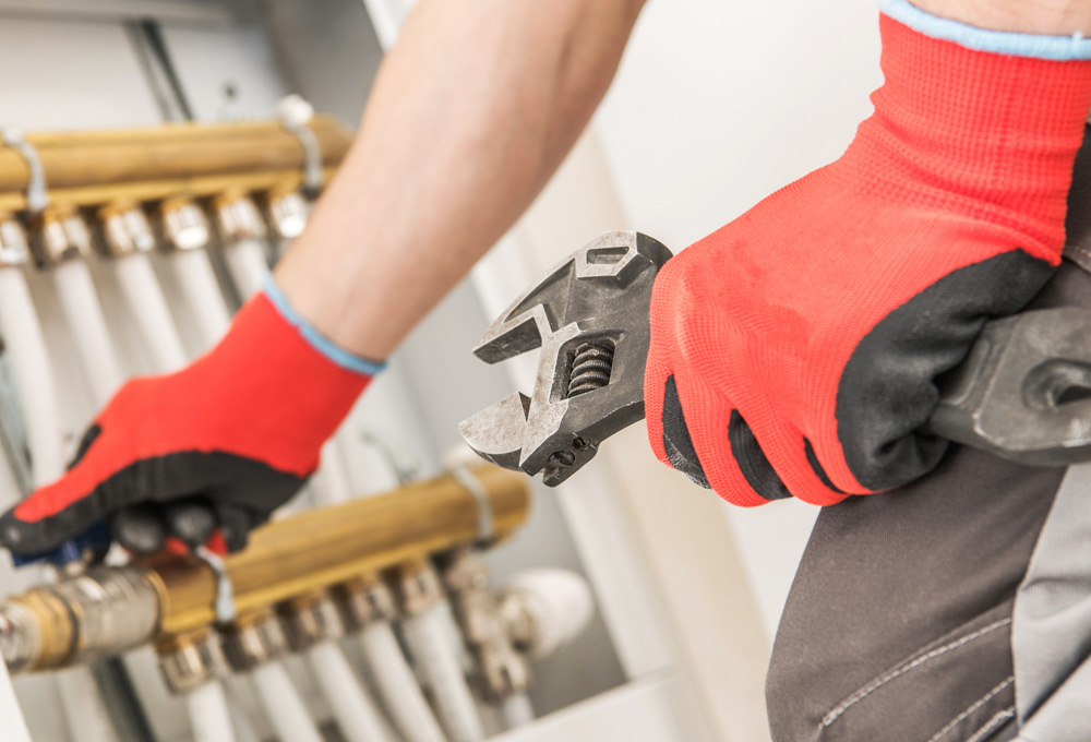 A Red Seal Plumber works on water lines with his wrench