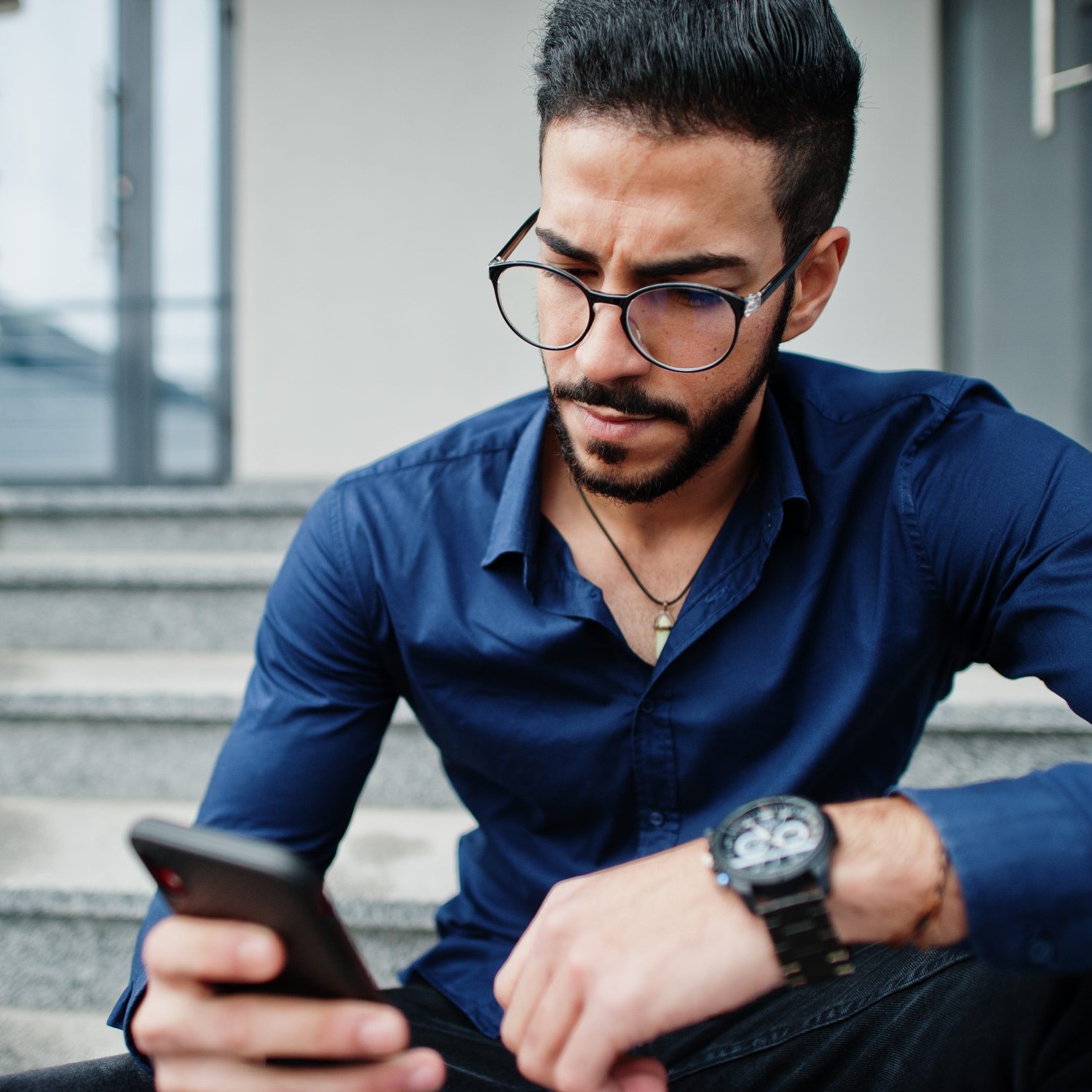 A man sits on stairs staring at his phone after a challenging conversation