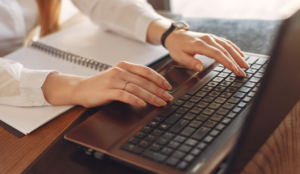 A woman sits at her desk writing a cover letter on her laptop