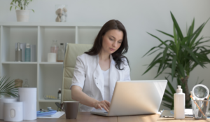 A woman works diligently from her desk on her laptop