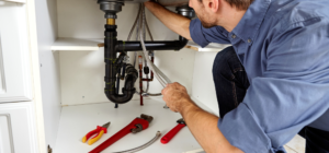 A plumber works underneath a sink