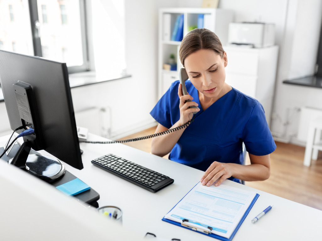 A Health Information Manager reviews paperwork at her desk.