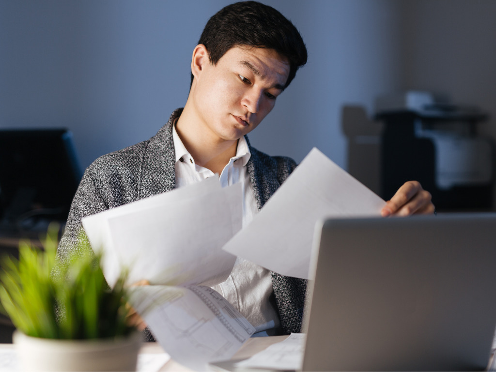 A man reviews paperwork at his desk